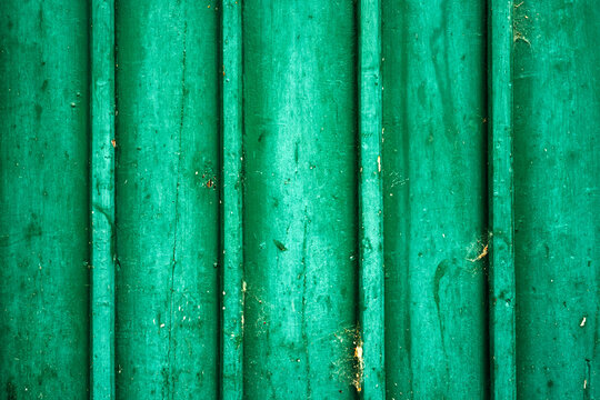 Grungy green textured wall with vertical corrugated panels and weathered paint.