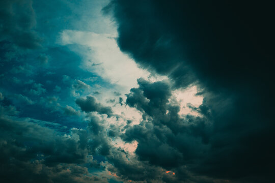 Moody, dramatic storm clouds sweep across a turbulent evening sky, creating strong contrast and a sense of impending weather.