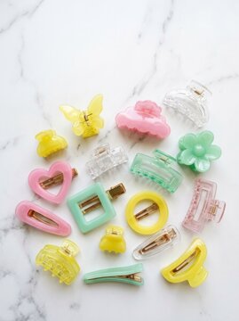 A collection of colorful pastel hair claw clips and stylish barrettes arranged on a white marble background for fashion beauty.