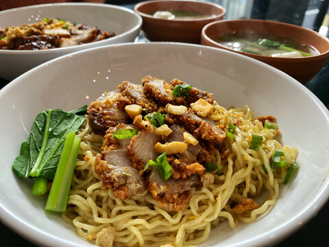 Bakmi Noodles with Crispy Roast Pork Belly and Green Vegetables in a Bowl