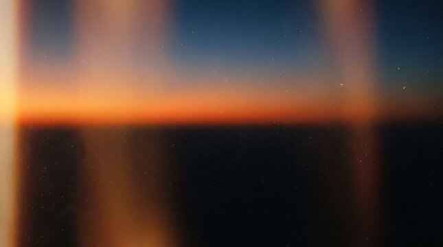 Vintage analog film light leak texture overlaying dusk sky during warm sunset to create nostalgic aesthetic