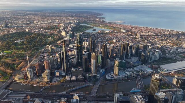 High aerial drone video over Melbourne CBD and Southbank at sunrise, showing the Yarra River, Royal Botanic Gardens, Albert Park Lake and Port Phillip Bay coastline