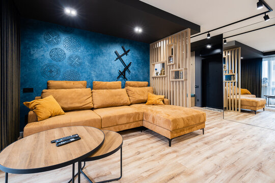 Ochre yellow sectional sofa against textured blue wall with stencils
