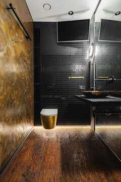Gold-leaf floating toilet bowl in dark textured bathroom