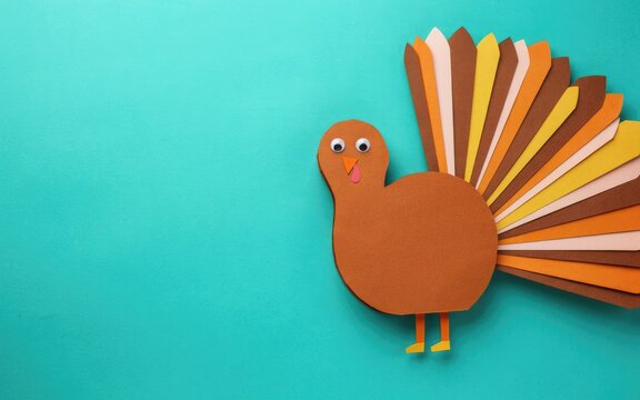 Handmade paper turkey craft for thanksgiving day celebration isolated on a bright teal blue background