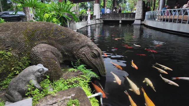 Carved stone dragon statue beside a koi pond at Ubud Monkey Forest, Bali
