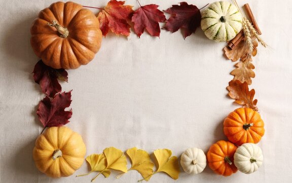 Flat lay frame of pumpkins and autumn leaves for a festive thanksgiving day background design concept