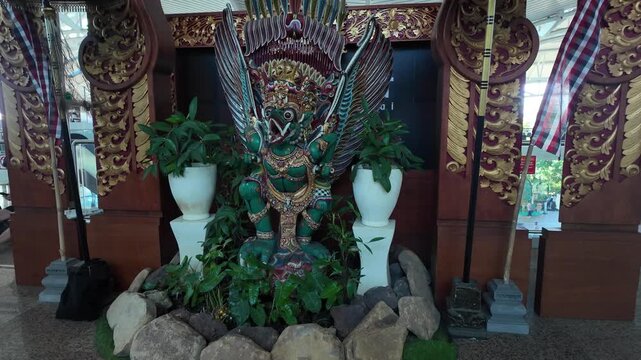 Green Garuda statue with ornate Balinese decor at Bali airport