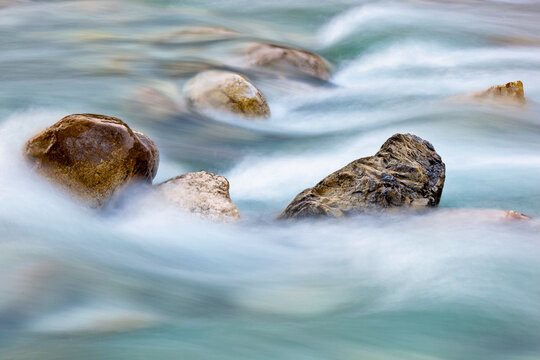 Rushing mountain river water flows around stones in an outdoor wilderness setting, promoting tourism and exploration in the Julian Alps Natural Park, Resia, Friuli Venezia Giulia, Italy, Europe view.