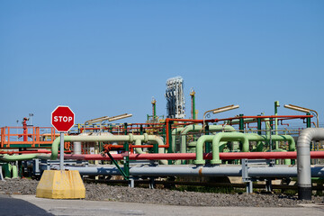 Naklejka premium Stop sign standing before industrial pipeline infrastructure