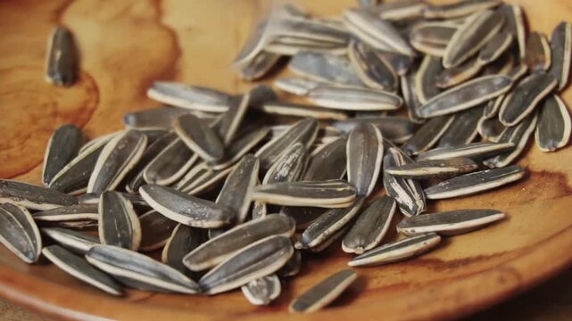 Slow motion footage of sunflower seeds dropping on the wooden table