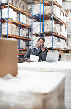 Phone call, cargo and laptop with man in warehouse for courier delivery, logistics schedule or inventory update. Quality control, client feedback and ecommerce with person and tech in factory