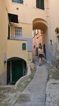 Cervo, liguria, italy. June 22, 2025. Female traveler with a backpack exploring the narrow, historic stone streets of cervo, an ancient seaside village in liguria, italy