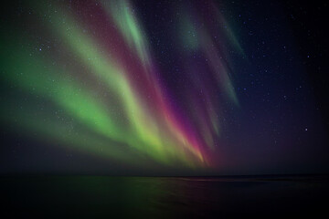Bight and intense Northern Lights Aurora Borealis in the dark night sky above Iceland and the Atlantic Ocean © Richard Waghorn