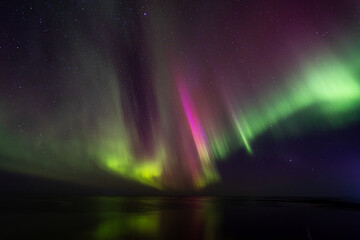 Bight and intense Northern Lights Aurora Borealis in the dark night sky above Iceland and the Atlantic Ocean © Richard Waghorn