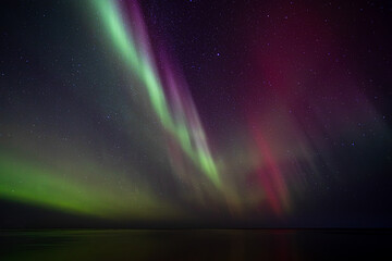 Bight and intense Northern Lights Aurora Borealis in the dark night sky above Iceland and the Atlantic Ocean © Richard Waghorn
