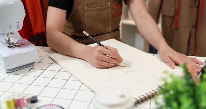 Fashion designer creating garment patterns, measuring fabric, inspecting clothing quality, and preparing apparel in a professional studio for tailoring, production, and fashion design workflow.