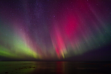 Bight and intense Northern Lights Aurora Borealis in the dark night sky above Iceland and the Atlantic Ocean © Richard Waghorn