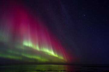 Bight and intense Northern Lights Aurora Borealis in the dark night sky above Iceland and the Atlantic Ocean © Richard Waghorn