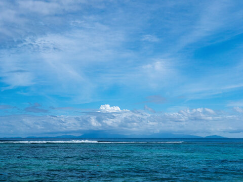 View of the ocean from La Digue Island. The silhouette of Praslin Island can be seen on the horizon.