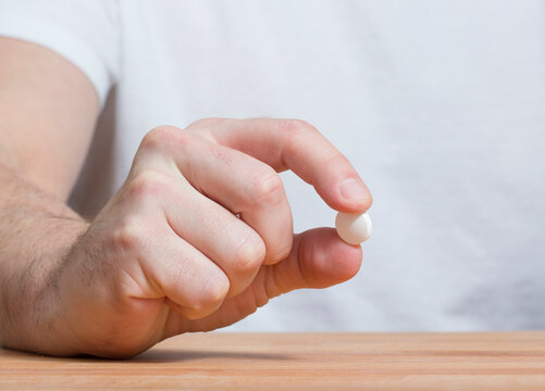 An unidentified caucasian man is offering a white pill.