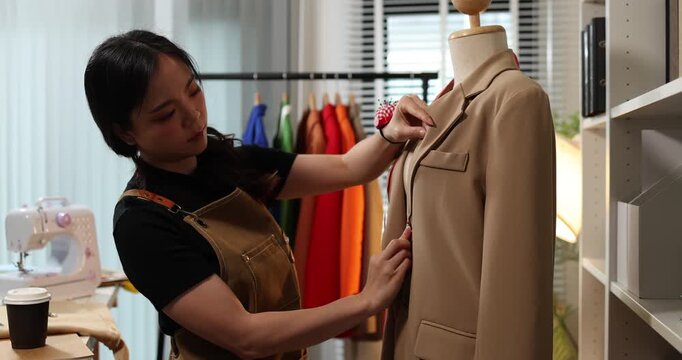 Fashion designer creating garment patterns, measuring fabric, inspecting clothing quality, and preparing apparel in a professional studio for tailoring, production, and fashion design workflow.