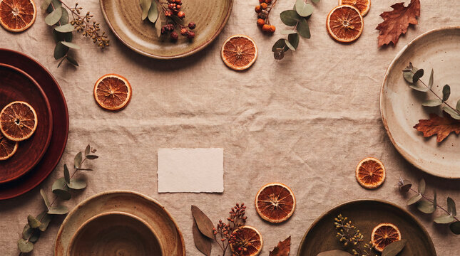 Rustic Thanksgiving table flat lay with ceramic plates dried oranges and eucalyptus copy space