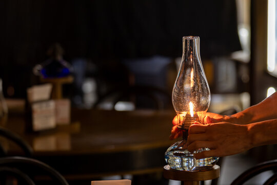 Hands holding a lit traditional oil lamp in a dark room
