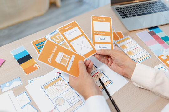Designer arranging wireframes, interface components, and color palettes to develop UX and UI concepts, supporting product design, user experience planning, and digital application development.
