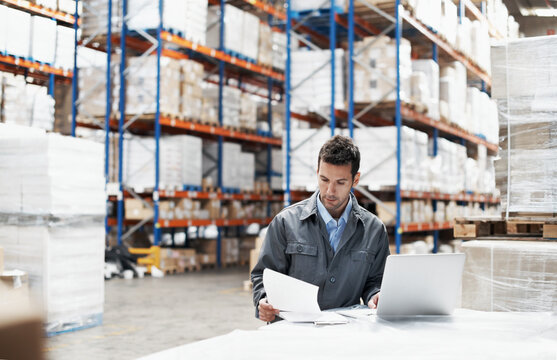 Laptop, logistics and documents with man in warehouse for delivery route, shipping schedule and order. Planning, ecommerce depot and checklist with employee and tech in factory for cargo procurement