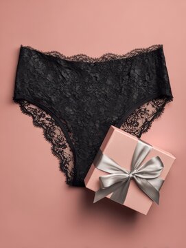 Black lace lingerie and pink gift box with ribbon on pink background