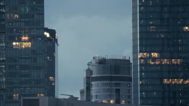 Modern office skyscraper buildings business district interior window lights night. High angle view showing illuminated glass windows of modern corporate office skyscrapers in a financial district