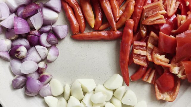 Chopped Shallots Garlic Red Chili Peppers and Tomatoes arranged on Plate for Cooking Ingredients