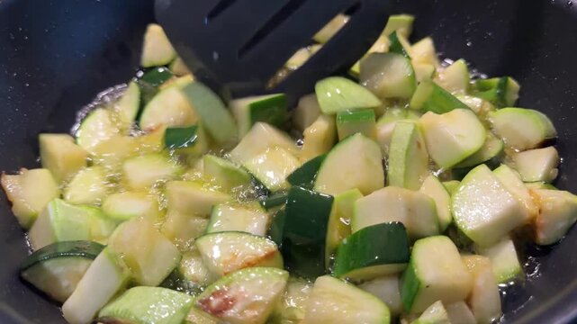 4K close-up video of diced zucchini and other fresh vegetables sizzling and cooking in a pan, showing natural textures, steam, and appetizing motion&mdash;perfect for cooking, meal prep, and healthy food co