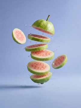 Fresh tropical fruit concept illustration with floating red guava slices and liquid splash, healthy food background