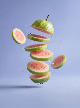 Fresh tropical fruit concept illustration with floating red guava slices and liquid splash, healthy food background