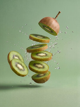 Fresh kiwi with floating kiwi slices and liquid splash, healthy food background