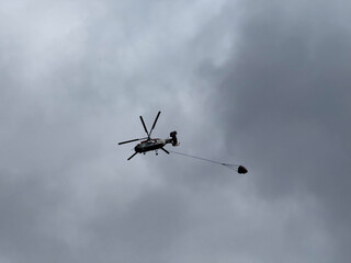 helicopter flying bucket cloudy sky, concept of emergency, construction. copyspace © Volha