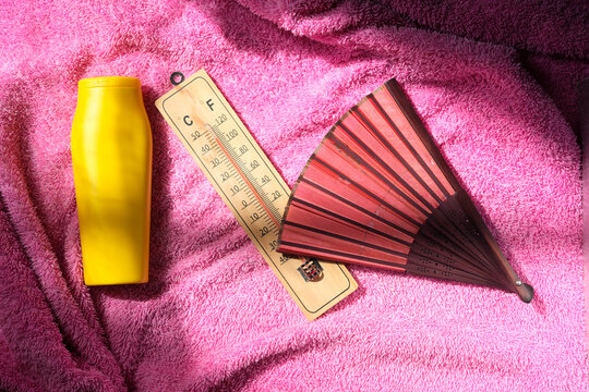 Global Heat wave during the summer holidays and vacation,  thermometer,displaying high temperature, a fan and sun blocker lotion