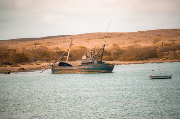 Old, rusty blue fishing boat anchored in turquoise water near the arid coast of Sal Island, Cape Verde. © Gulyas