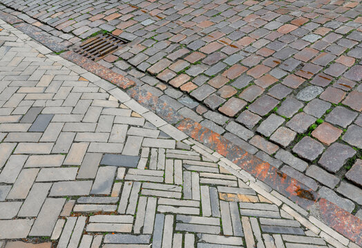 Historic cobblestone street with herringbone pavement, curb and storm drain