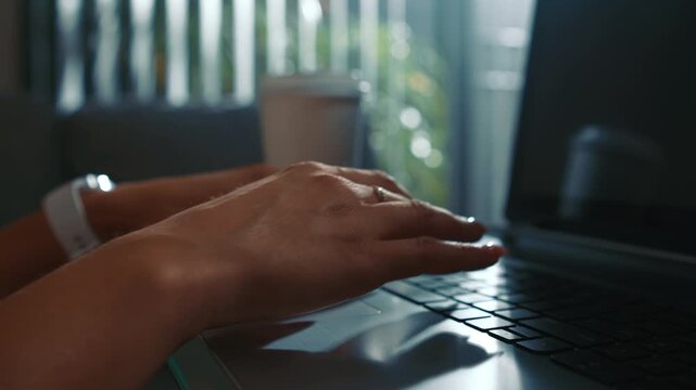 Woman hands typing on laptop at home with coffee near window close up focused entering text and completing tasks in natural daylight home environment