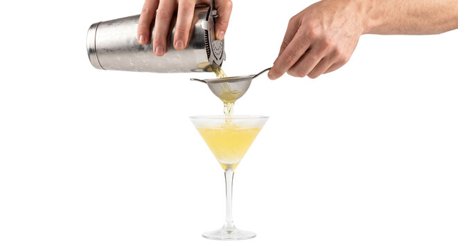 Bartender straining a yellow cocktail into a martini glass with a fine mesh sieve
