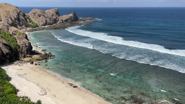  High angle view of sandy beach, ocean and rocks.