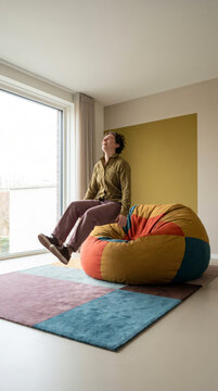Woman laughing as she jumps onto a colorful patchwork beanbag in a bright room