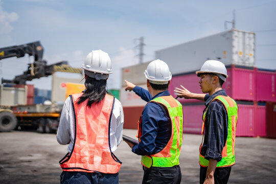 Three logistics workers discussing container handling operations at shipping yard. Team planning, cargo coordination, container terminal management, freight logistics, port operations, supply chain.