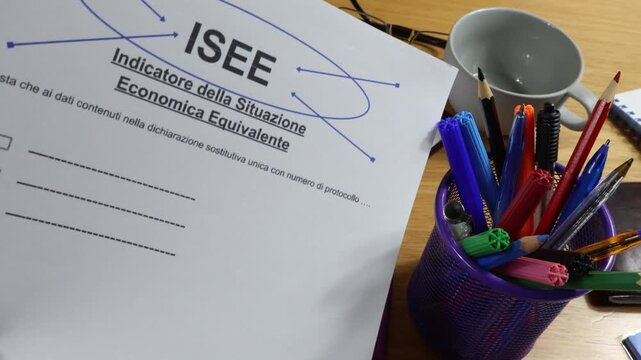 A printed ISEE form, close-up, on a desk with a marker in a man's hand. This is an Italian concept for the indicator of the economic situation in Italy.