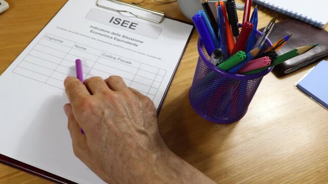 Close-up of a printed ISEE form on a desk with a marker in a man's hand. Italian culture is a bonus during the crisis.
