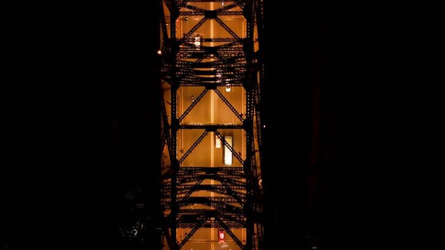 Top down night aerial drone video of vehicles moving on illuminated Howrah Bridge through its iconic steel truss structure in Kolkata, showcasing urban transport and architecture.