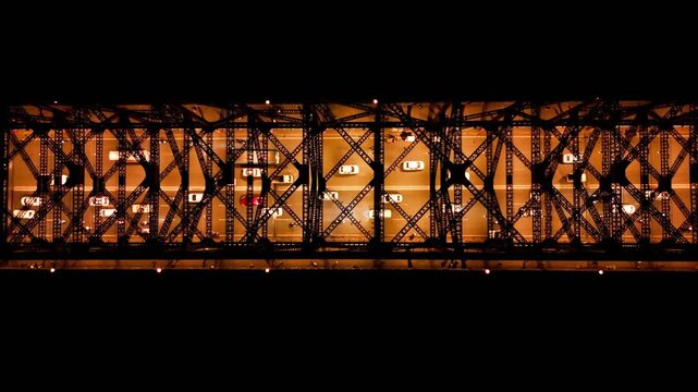 Top down night aerial drone video of vehicles moving on illuminated Howrah Bridge through its iconic steel truss structure in Kolkata, showcasing urban transport and architecture.